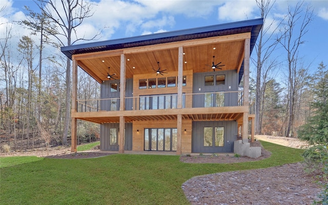 rear view of property featuring a yard, board and batten siding, a balcony, and a ceiling fan