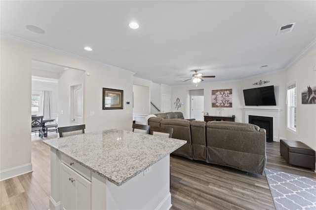 kitchen with a fireplace, visible vents, open floor plan, white cabinets, and wood finished floors