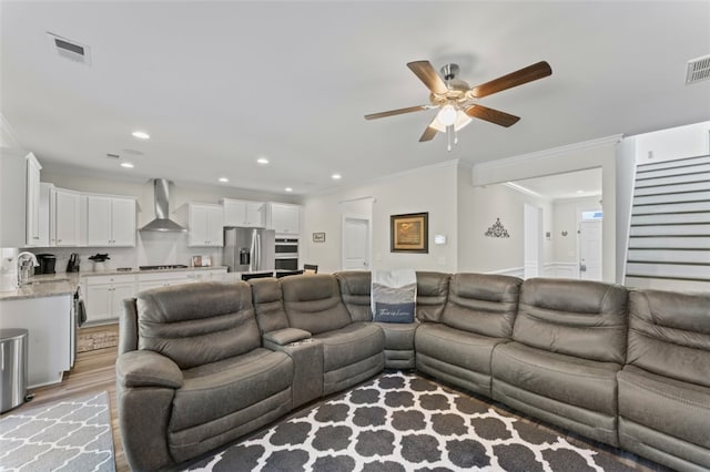 living room featuring ornamental molding, recessed lighting, visible vents, and light wood finished floors