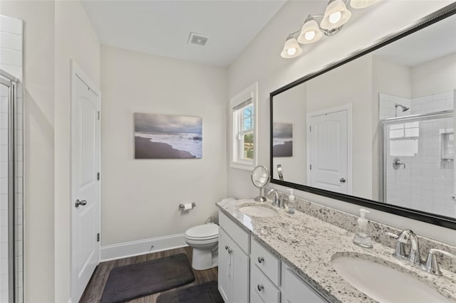 full bath with a stall shower, a sink, baseboards, and wood finished floors