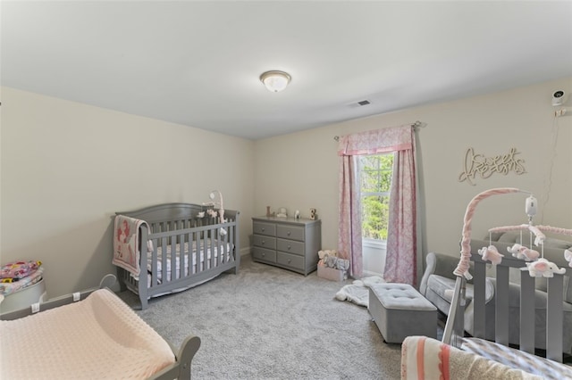 bedroom featuring a nursery area, visible vents, and light carpet