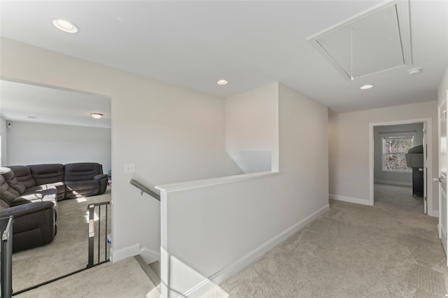 hallway with attic access, baseboards, light colored carpet, and an upstairs landing