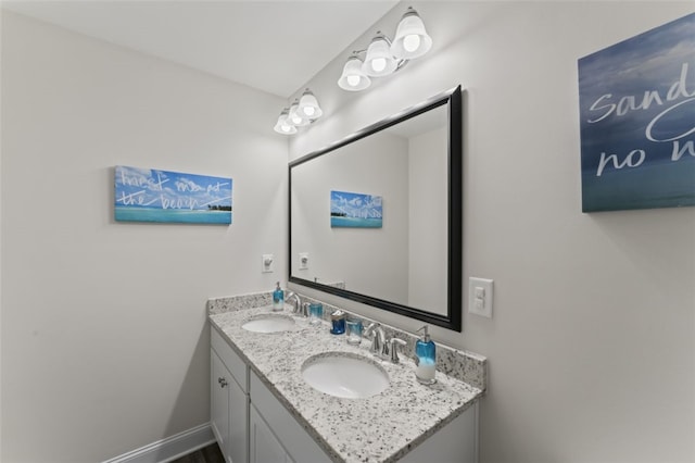 bathroom featuring double vanity, baseboards, and a sink