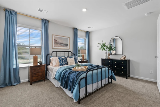 carpeted bedroom with visible vents, baseboards, and multiple windows