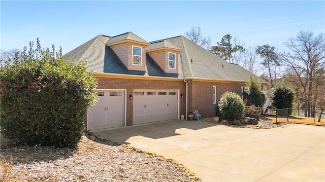 view of front of home featuring a shingled roof, concrete driveway, an attached garage, fence, and brick siding