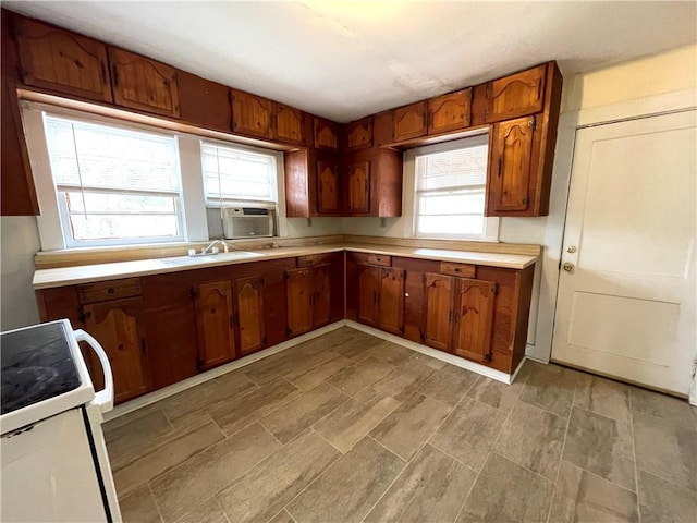 kitchen featuring cooling unit, white electric range, light countertops, and a sink