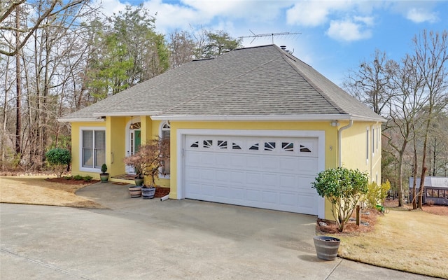 ranch-style home featuring a garage, a shingled roof, and stucco siding