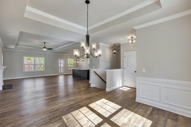 unfurnished dining area with ornamental molding, dark wood-style flooring, a raised ceiling, and a decorative wall