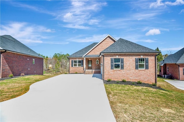 view of front of property with central AC, a front lawn, roof with shingles, and brick siding