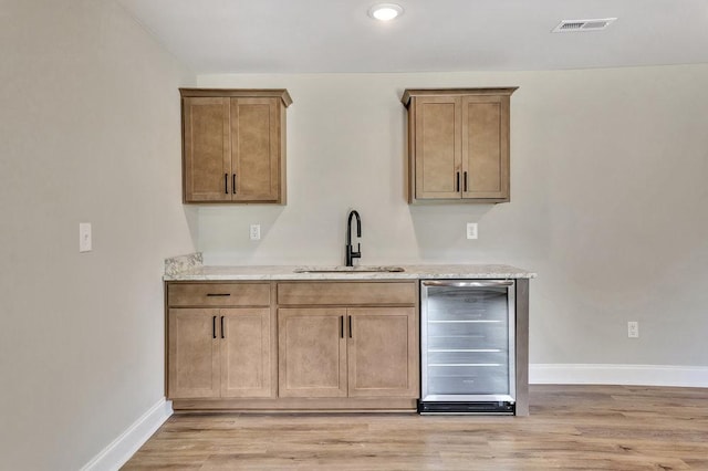 kitchen with beverage cooler, visible vents, a sink, and light wood-style flooring