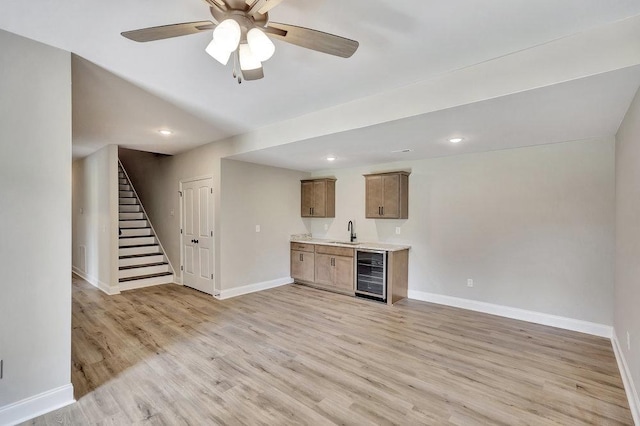 interior space featuring beverage cooler, baseboards, stairs, light wood-type flooring, and a sink