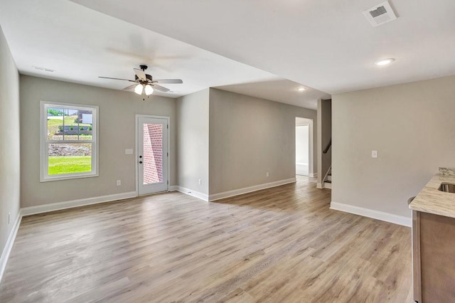 unfurnished living room featuring light wood-type flooring, stairway, visible vents, and baseboards