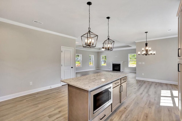 kitchen with hanging light fixtures, light wood-type flooring, built in microwave, and open floor plan