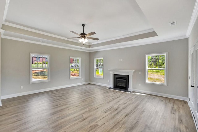 unfurnished living room featuring light wood-style floors, a fireplace with flush hearth, visible vents, and a raised ceiling