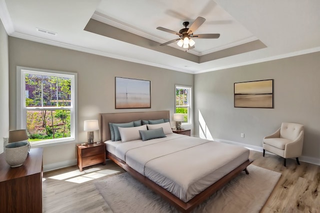 bedroom with multiple windows, visible vents, and a raised ceiling