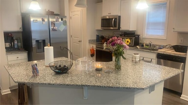 kitchen featuring a kitchen breakfast bar, stainless steel appliances, an island with sink, and pendant lighting