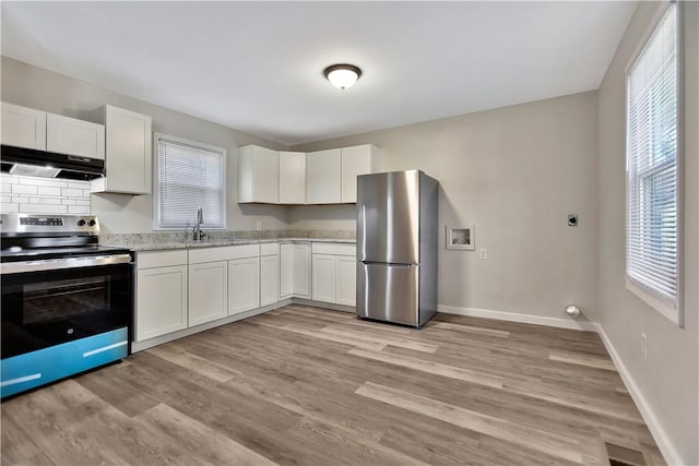 kitchen featuring light wood-style flooring, appliances with stainless steel finishes, white cabinetry, a sink, and under cabinet range hood