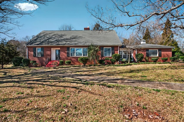 view of front of house with a front lawn, a chimney, and brick siding