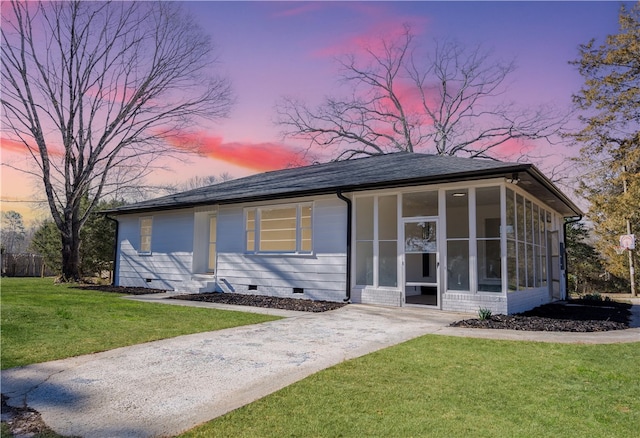 view of front of home with crawl space, a sunroom, a lawn, and roof with shingles