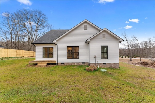 rear view of house with a shingled roof, crawl space, a lawn, and fence