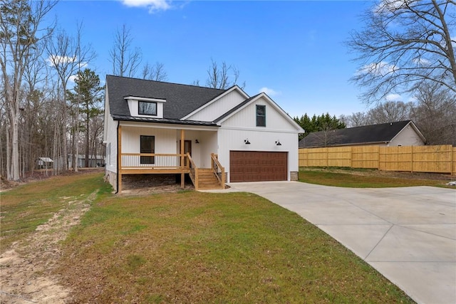 modern farmhouse style home featuring driveway, a porch, a front yard, and fence