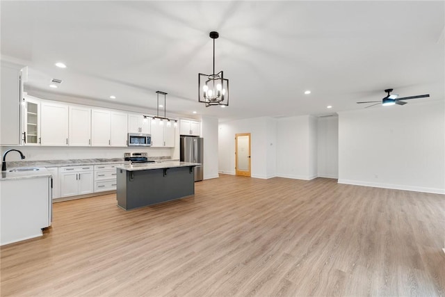 kitchen featuring a center island, decorative light fixtures, stainless steel appliances, light countertops, and open floor plan