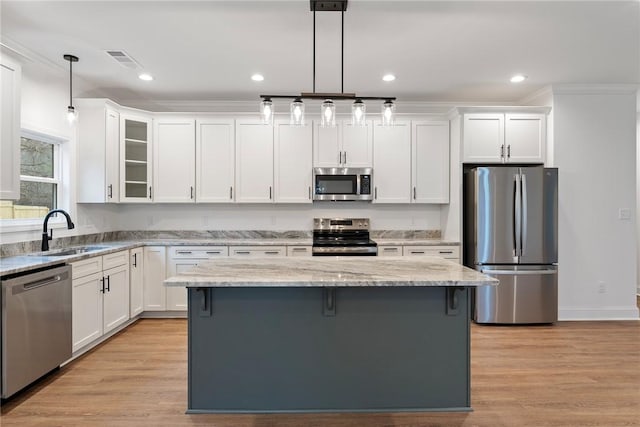 kitchen with stainless steel appliances, hanging light fixtures, a kitchen island, and white cabinetry