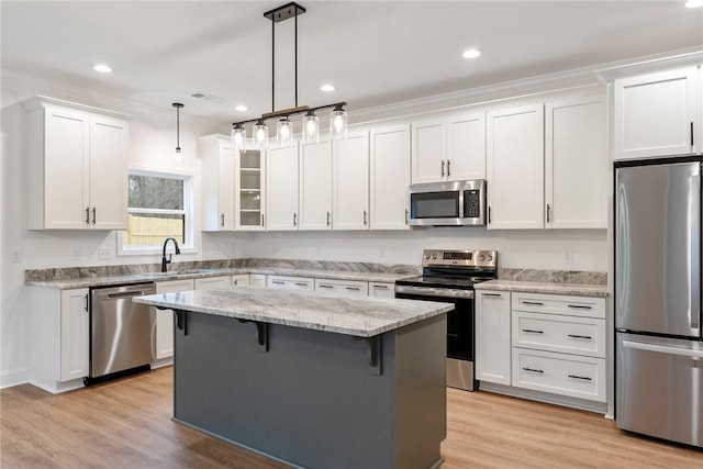 kitchen with a center island, hanging light fixtures, stainless steel appliances, a kitchen bar, and white cabinetry