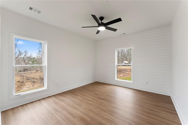 empty room featuring visible vents, baseboards, ceiling fan, and wood finished floors