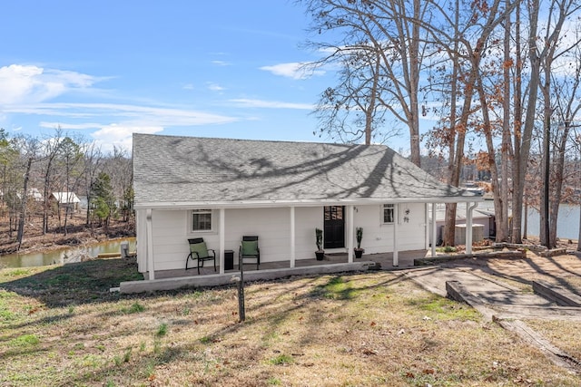 rear view of property with a yard, roof with shingles, and a patio area