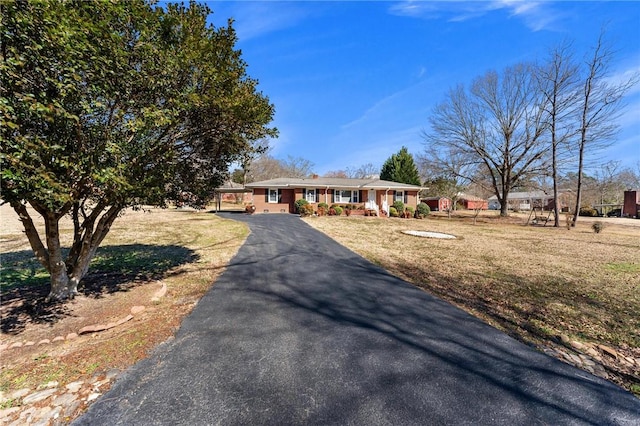 single story home featuring aphalt driveway, a front yard, and covered porch