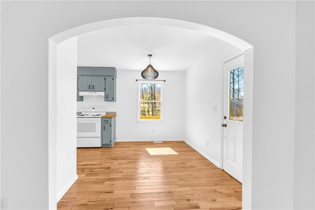 unfurnished dining area with light wood-type flooring, baseboards, and arched walkways