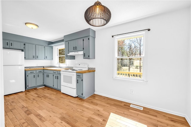 kitchen featuring visible vents, white appliances, light wood-style flooring, and decorative light fixtures