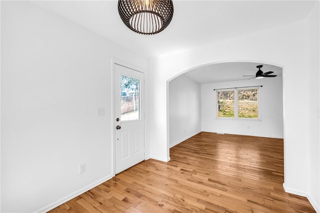 foyer with a healthy amount of sunlight, light wood-style floors, arched walkways, and a ceiling fan