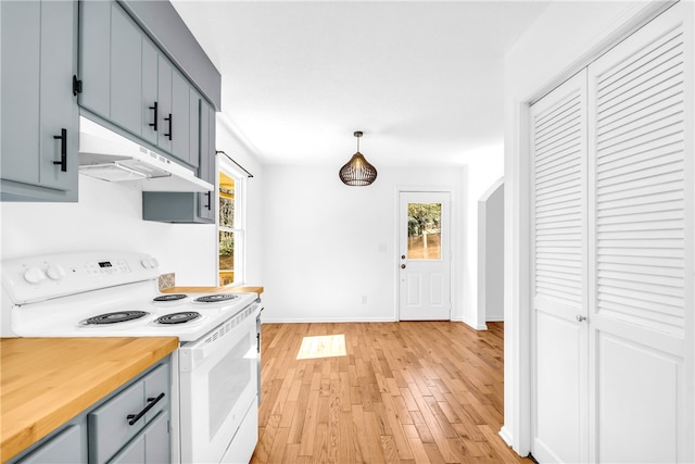 kitchen with arched walkways, white electric stove, hanging light fixtures, light wood-style floors, and under cabinet range hood