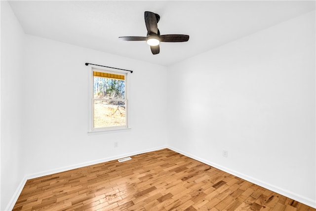 spare room with light wood-type flooring, a ceiling fan, and baseboards