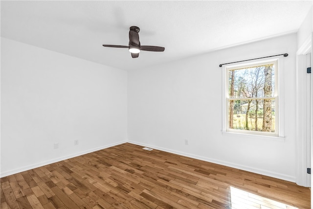 unfurnished room with ceiling fan, wood finished floors, and baseboards