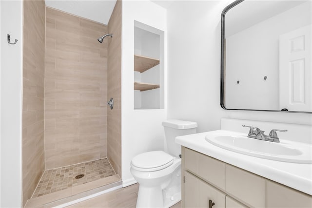 bathroom with tiled shower, vanity, and toilet