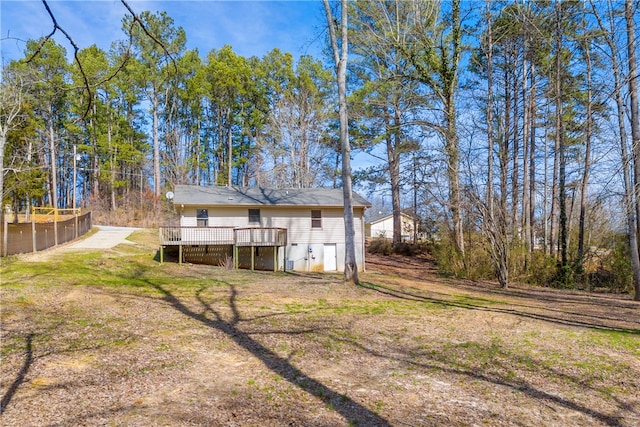 rear view of property with a yard, a wooden deck, and fence