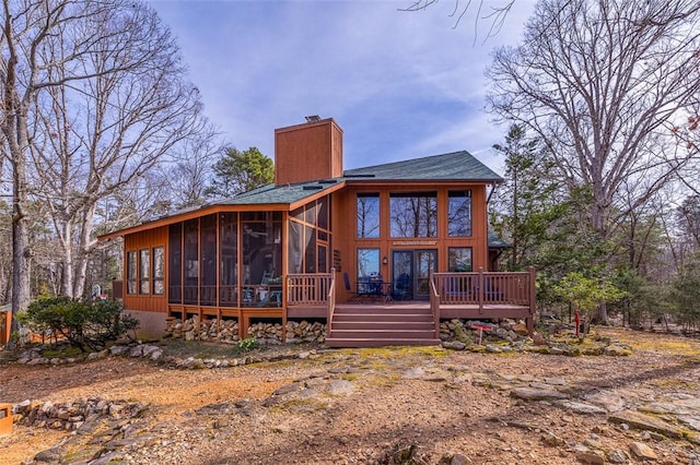 rear view of property featuring a sunroom, a chimney, and a wooden deck