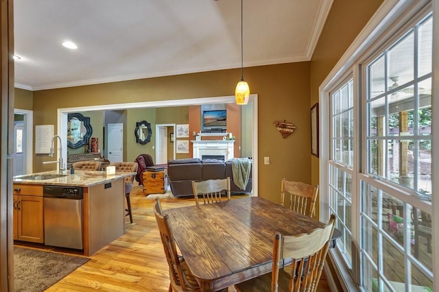 dining space featuring crown molding, a fireplace, and light wood-style floors