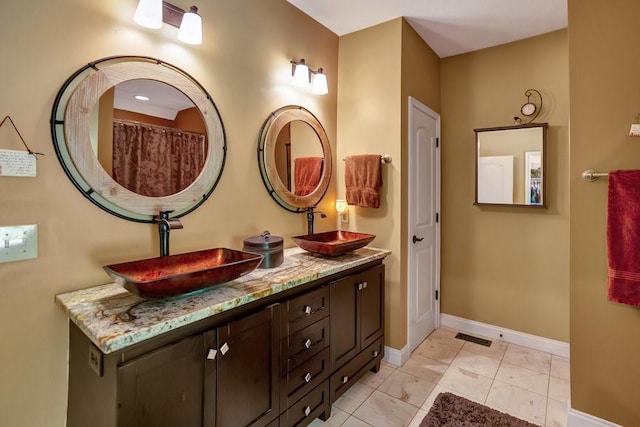 full bath with visible vents, a sink, baseboards, and double vanity