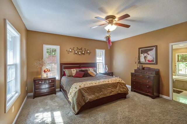 bedroom featuring ceiling fan, baseboards, ensuite bathroom, and light colored carpet