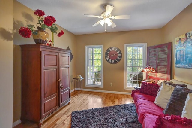 living area featuring light wood-style floors, baseboards, and a ceiling fan