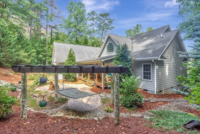 rear view of house featuring a shingled roof and crawl space