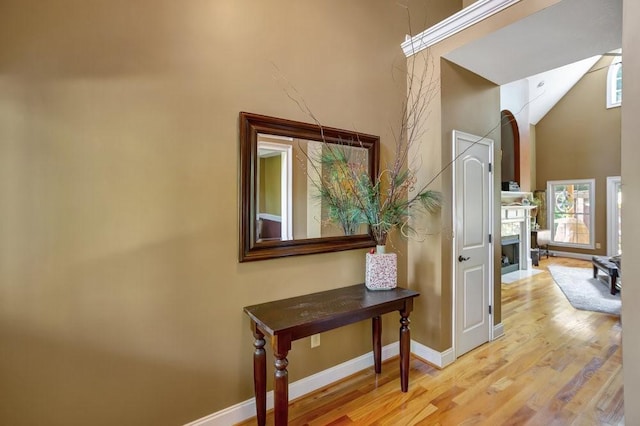 hallway featuring light wood-style floors, a high ceiling, and baseboards