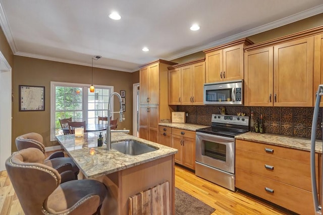 kitchen featuring a center island with sink, appliances with stainless steel finishes, a breakfast bar, light stone counters, and hanging light fixtures