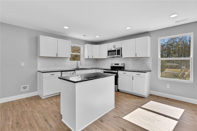 kitchen with tasteful backsplash, appliances with stainless steel finishes, a sink, and baseboards