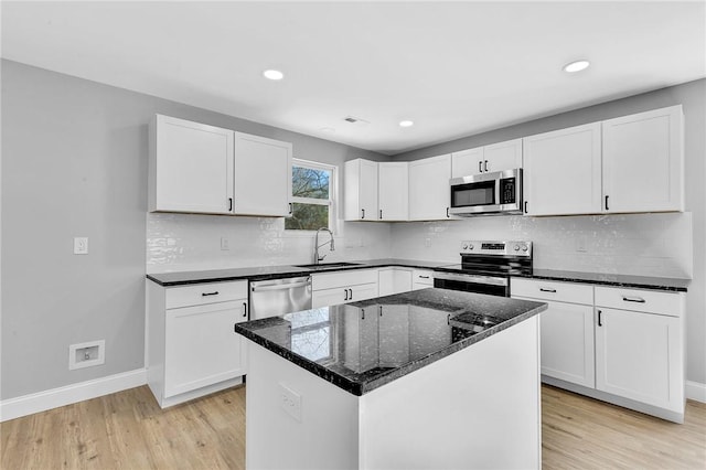 kitchen featuring decorative backsplash, stainless steel appliances, light wood-style floors, white cabinetry, and a sink