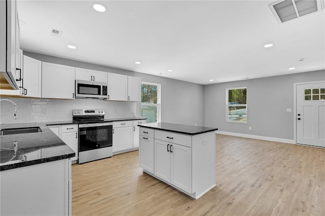 kitchen featuring appliances with stainless steel finishes, light wood-style floors, visible vents, and a sink